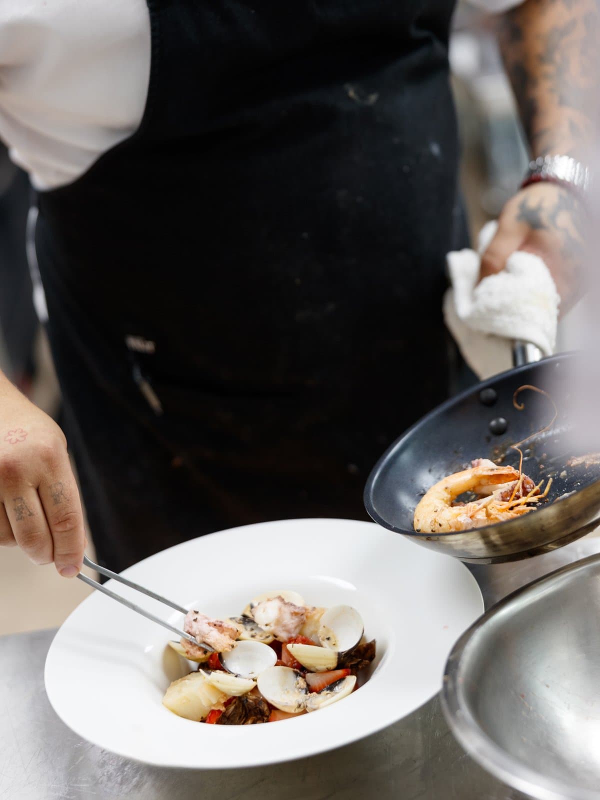Chef plating a seafood dish on the line at Thanks to Harrison